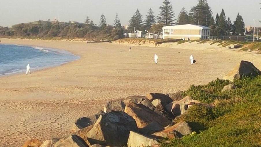 HAZARD: Newcastle City Council workers collecting asbestos fragments off Stockton beach in July. 