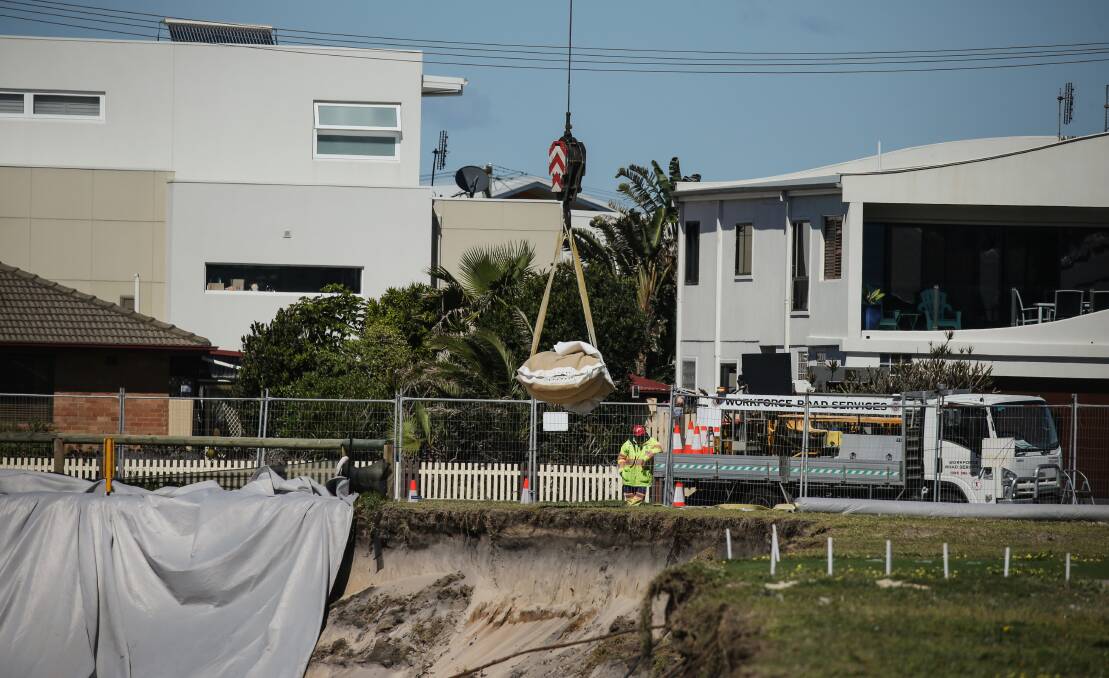 SHIFTING SANDS: Workers use a crane to install large sandbags along Stockton beach as a temporary measure to protect homes and roads from worsening erosion. Picture: Marina Neil
