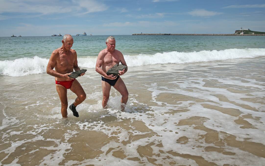 HIDDEN DANGER: Stockton Surf Life Saving Club members Noel Burns, left, and Ken Grainger removing large rocks from the water on Tuesday afternoon. Picture: Marina Neil
