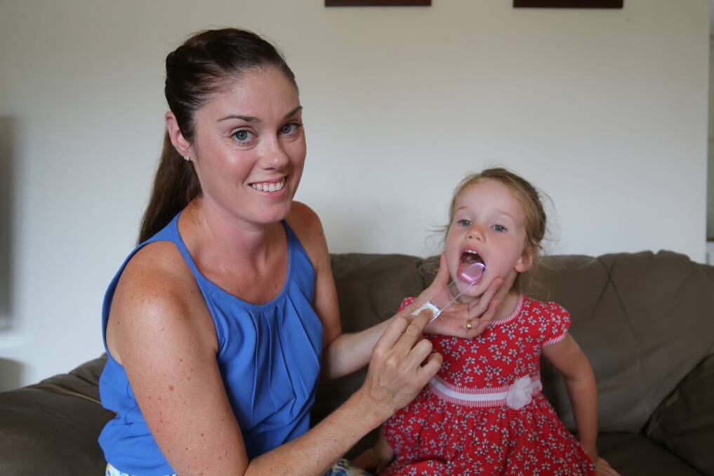 Game-changing idea: Jennifer Holland at home in 2015 demonstrating her original invention, the Throat Scope, on her daughter. Picture: Ryan Osland. 