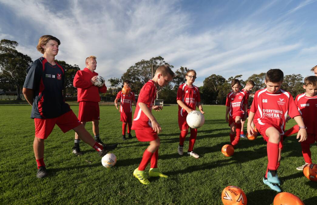 Game on: "He is honey to the bees for soccer kids," says David Romeo, holding ball, of Liam McDonald, left, at training. Picture: SImone de Peak. 