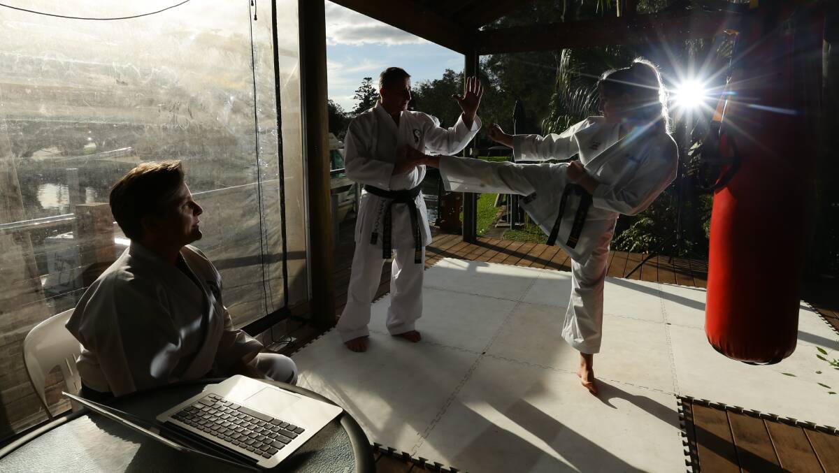 Home training: Brian Hayes, founder of Hunter Valley Martial Arts, spars with his daughter Kaia as his wife, Sandy, looks on. Picture: Jonathan Carroll 