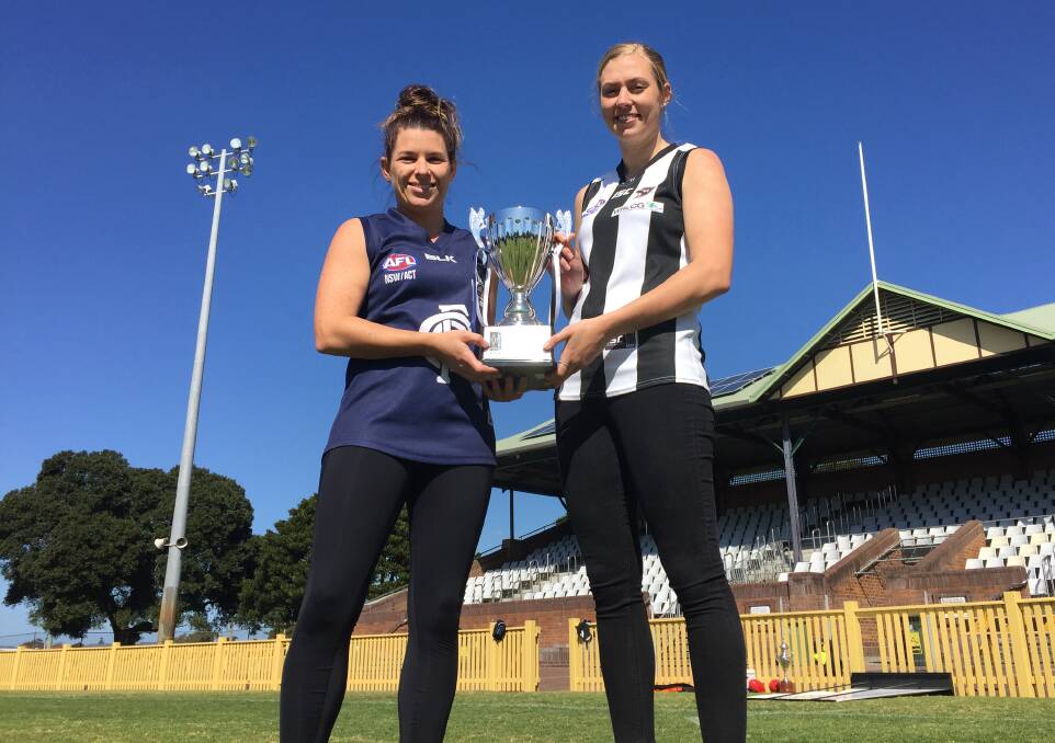 BATTLE READY: Newcastle City captain Ash Hayllar and Wyong Lakes skipper Rebecca Ives with the Black Diamond AFL women's premiership trophy at No.1 Sportsground on Thursday. Picture: Josh Callinan
