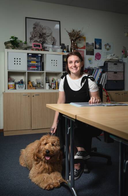 GROWTH: Laura Perceval now works at the school as a wellbeing support worker, pictured with support dog Juno. Picture: Marina Neil