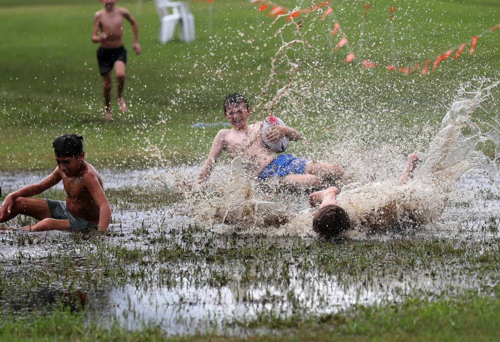 WET AND WILD: Kids make the most of the weekend's wet weather with a splash. Photo: Peter Lorimer 
