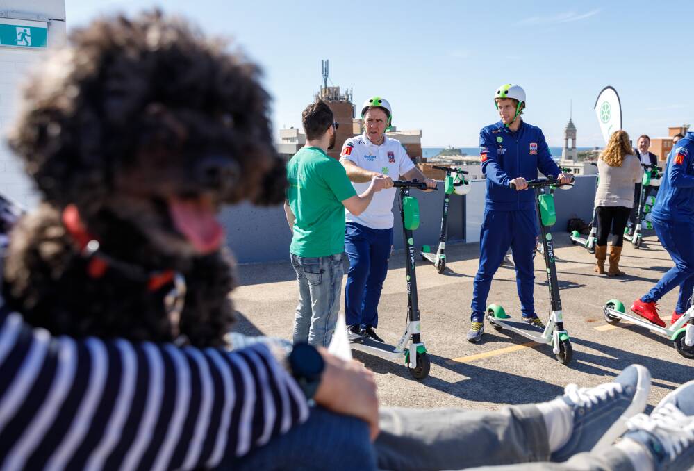 READY TO ROLL: Newcastle Jets CEO Lawrie McKinna and player Lachlan Jackson get a safety briefing before trying out Lime share scooters. Picture: Max Mason-Hubers
