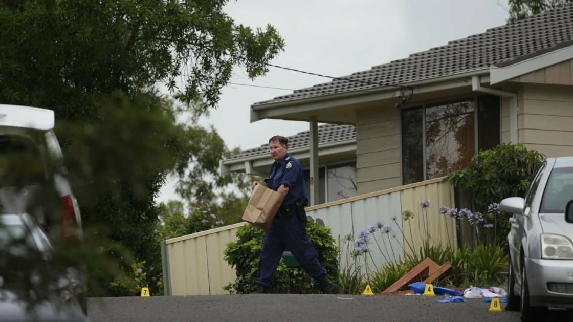 Evidence: A police officer carries evidence from the scene of the stabbing at Leumeah Place, Bolton Point. Picture: Simone DePeak
