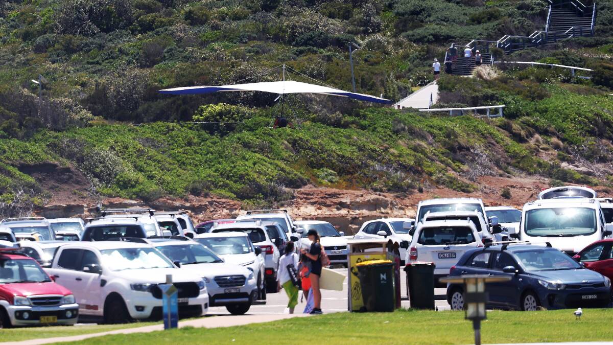 A hangglider drifts over parked cars at Bar Beach in December. Picture by Peter Lorimer