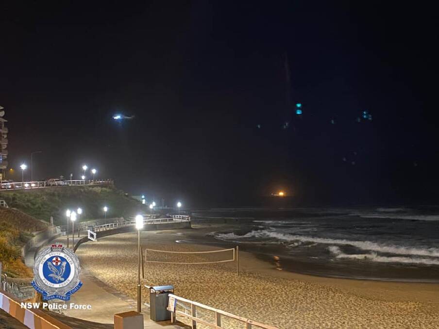 EYE IN THE SKY: A helicopter combs Newcastle beach on Wednesday night as part of the search effort. Picture: NSW Police