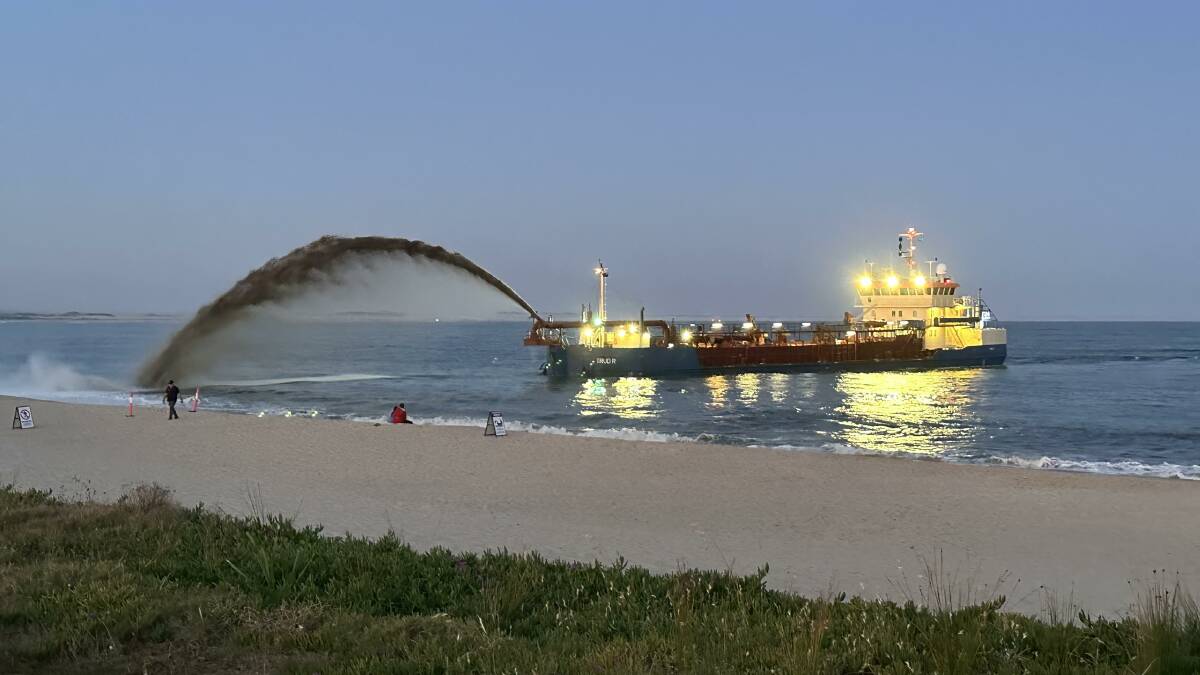 A dredge spraying sand at Stockton beach on Saturday. Picture by Simon Herd