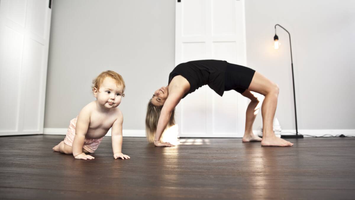FLEXIBLE CLASSES: New FM's Mel Sargeant practises yoga while her 12-month-old Summer Joy explores the room. Sargeant has set up a family friendly yoga space in Cardiff called The Ohana Room. Picture: April Werz