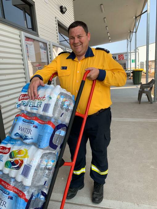 GRATEFUL: Rural Fire Service district manager Paul Best accepts a delivery of bottled water. Pictures: Supplied
