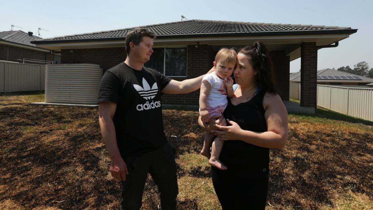 HOME THREAT: Mathew Collison and Aleisha Hodkinson with daughter Carly in their backyard at North Rothbury on Wednesday. Picture: Simone De Peak.