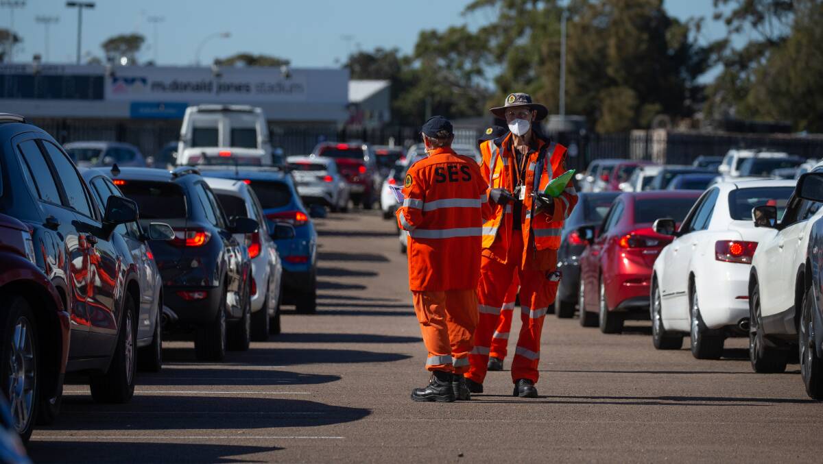 LONG WAIT: State Emergency Service workers at the McDonald Jones Stadium clinic on Saturday. Picture: Marina Neil