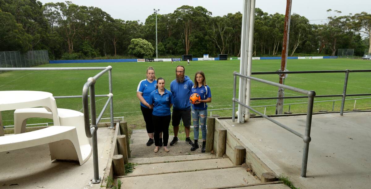 FUNDING MISS: Garden Suburb Football Club president Lenny Allen with female officials and players. The Landcom housing estate will be built in bushland shown beyond the playing field. Picture: Jonathan Carroll