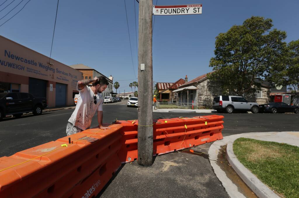 WHAT'S DOING: Local resident Nate Vittadello views the bizarre scene on Monday where City of Newcastle roadworks have left a power pole situated a few metres out from the kerb on the Foundry and Albert street intersection. Picture: Simone De Peak.