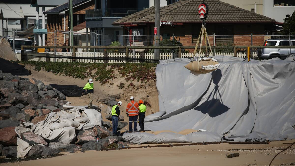 TEMPORARY: City of Newcastle workers move sand bags onto the beach earlier this month. Picture: Marina Neil