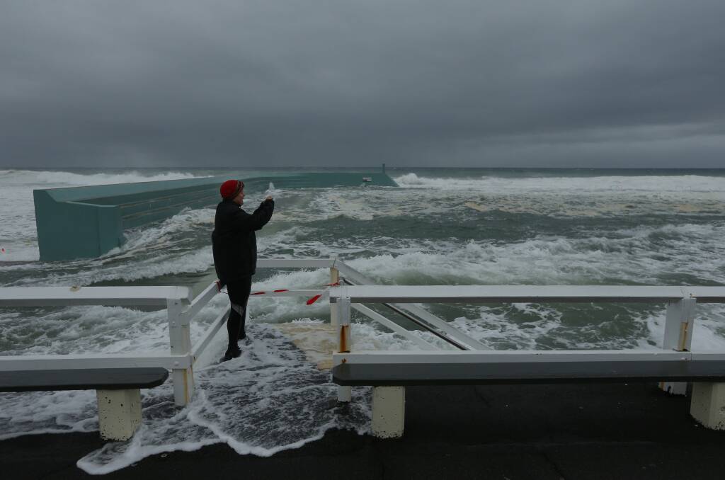 STORMY: A woman inspects the intense conditions at Newcastle Ocean Baths on Sunday morning. 