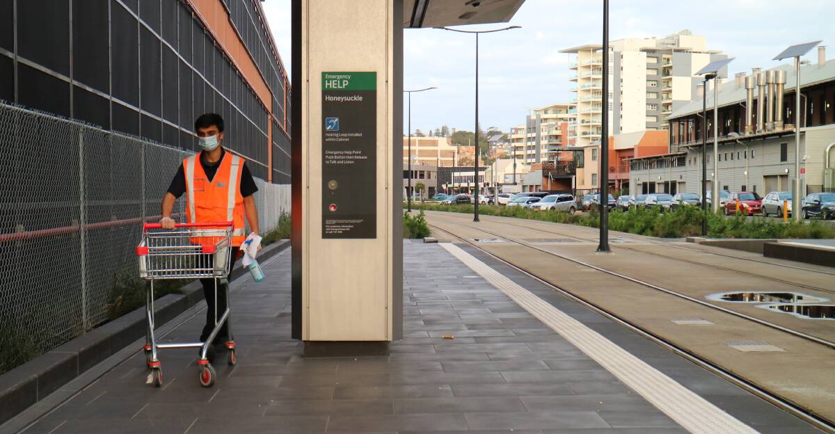EXTRA CARE: A cleaner wearing a mask at the Honeysuckle light rail stop. Picture: Jonathan Carroll
