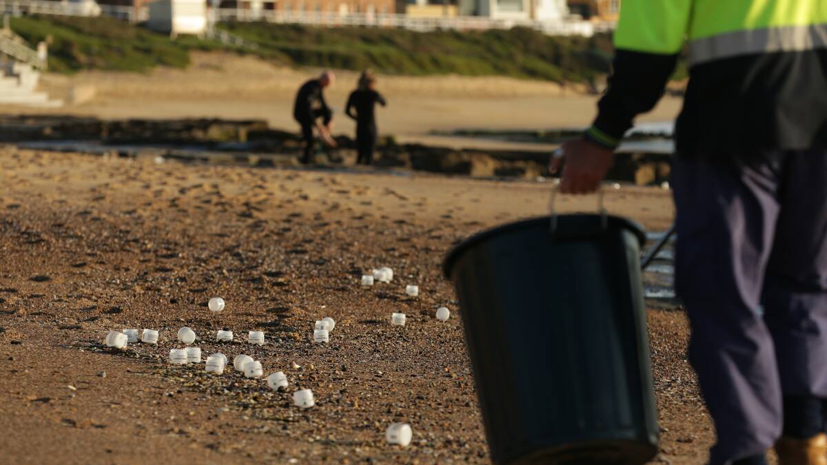 WASH UP: A worker picks up plastic off Merewether beach. Picture: Simone De Peak