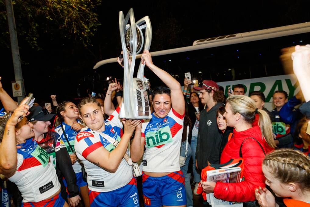 Catilan Johnston and Millie Boyle carry the NRLW trophy off the team bus last season. Picture by Max Mason-Hubers