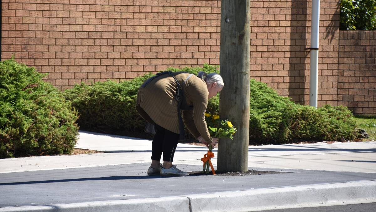 TRIBUTE: A worker lays flowers on Wednesday morning. Picture: Max McKinney