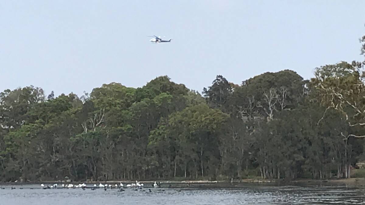 A police helicopter searches Budgewoi Lake for the missing kayaker. Picture: Joanne McDonald 