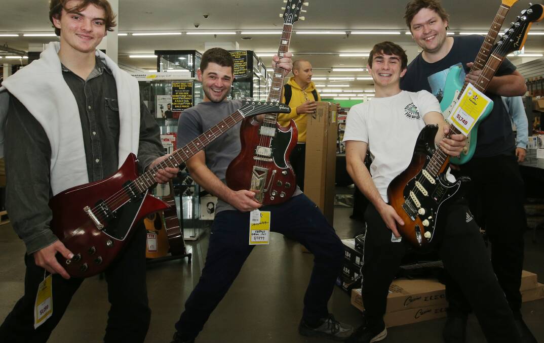 Banjo Longworth with his custom Gibson guitar, pictured with Pat Reilly of Jesmond, Dominic Matthews of Maitland and Sam Rush of Dungog, who all snagged a bargain on Thursday. Picture by Simone De Peak