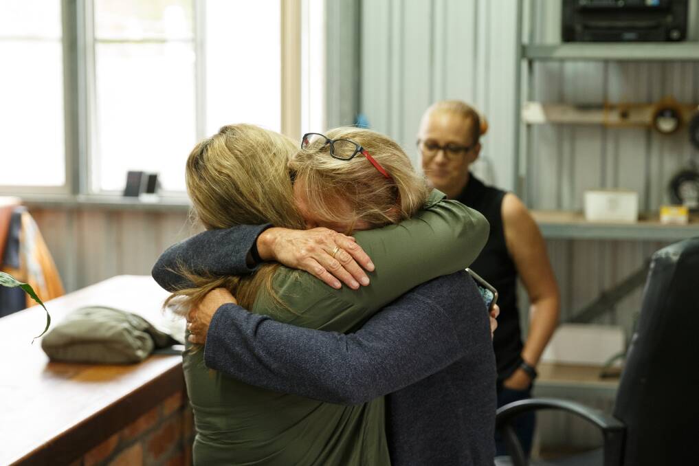 "WE WON": Kim Smith and Sue Walker hug at the Clout family's business in Fullerton Cove, celebrating the announcement that their class action has reached an in-principle agreement toward settlement. Photo: Max Mason-Hubers