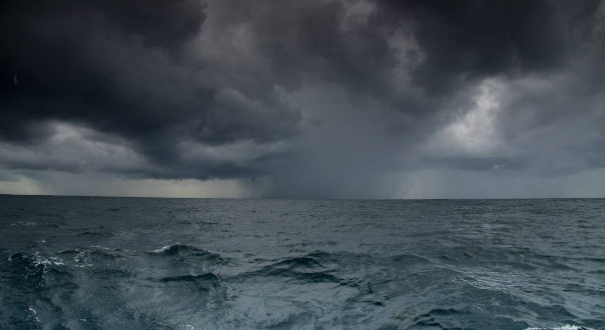 ON BOARD: Rain moves across the horizon just off the Port Stephens coast. On board a 54 ft catamaran, whale watchers are keen to see the first humpbacks of the season as the northern migration gets underway. Photo: Simon McCarthy