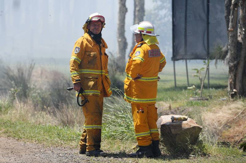 Former prime minister Tony Abbott (left) is seen with his Davidson Brigade as NSW Rural Fire Service crews battle a bush fire burning near houses along Lemon Tree Passage Road, in Salt Ash, NSW, Friday. Photo: AAP/Dan Himbrechts