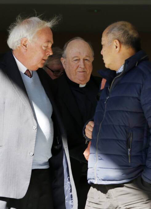 Appeal: Archbishop Philip Wilson outside Newcastle Courthouse on Tuesday with 'Old Boy' classmate supporters, including (left) the supporter who called Peter Gogarty 'rubbish'. Picture: Darren Pateman.