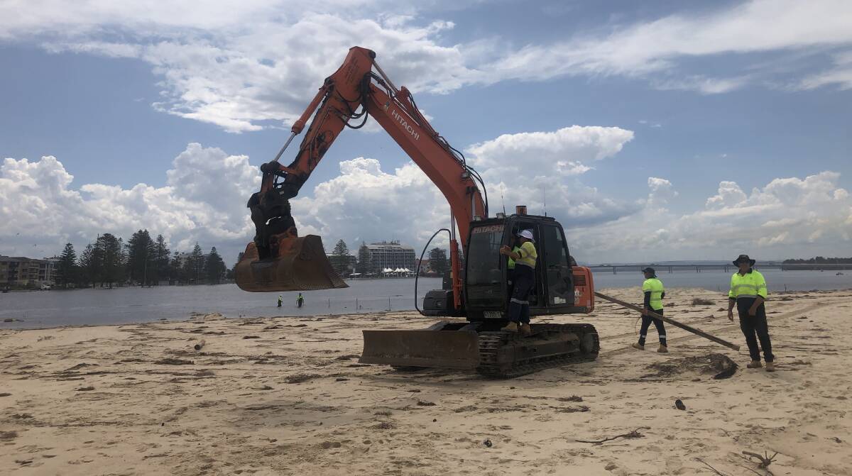 Funding: Central Coast Council staff on Tuesday prepare to open a second channel between Tuggerah Lakes and the ocean after unprecedented flooding. The NSW Government has announced funding for a dredge to remove sand from the channel area.