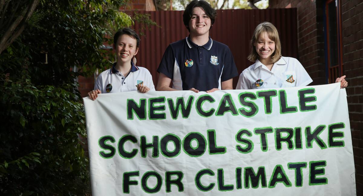 Call: Hunter high school students Alexa Stuart, Kalleb Pritchard and Abby Manning with a banner ahead of today's Strike for Climate Action event in Newcastle's Civic Park from noon. Picture: Marina Neil. 