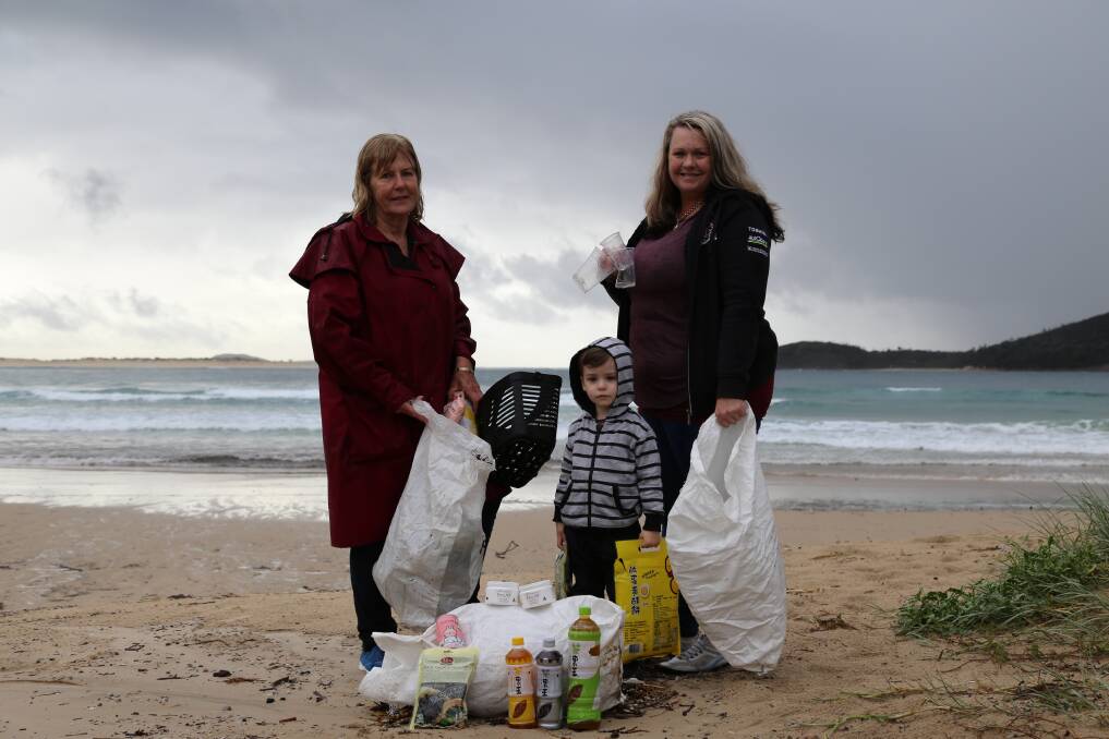 PITCH IN: Pamela Smith with Prue Bamford and her son Hudson Christesen, 3, with some of the debris cleaned up from Fingal Beach on Monday. Picture: Ellie-Marie Watts