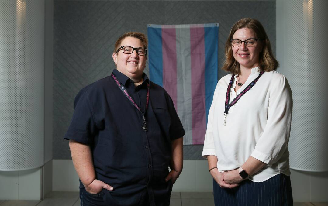 OUR LIVES: Hunter Gender Alliance vice president Jo Mills and president Dr Katie Wynne, a senior staff specialist at John Hunter Hospital, with a transgender pride flag. Picture: Marina Neil