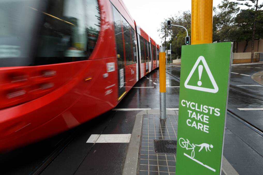 A temporary sign warning cyclists to take care on Scott Street, outside the cafe, as a tram passes. Picture: Max Mason-Hubers