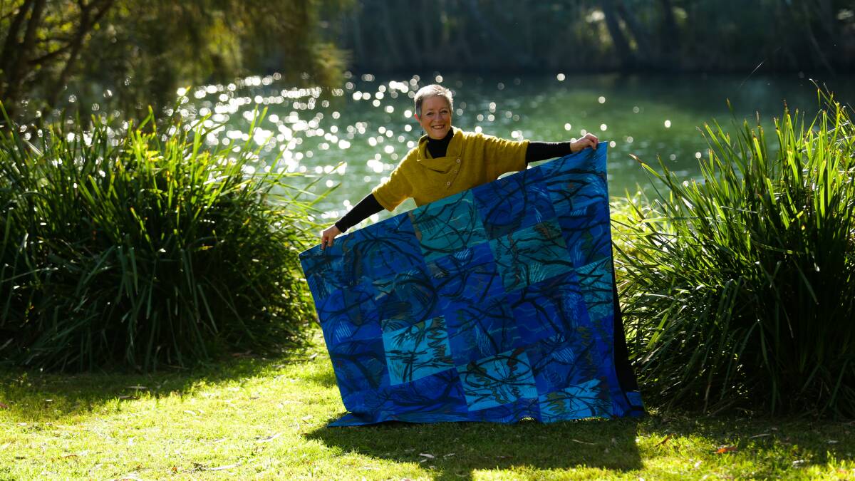CREATIVE FLOW: Textile artist Judy Hooworth with her quilt, 'Creek Drawing #14', with the source of inspiration - Dora Creek - behind her. Picture: Jonathan Carroll