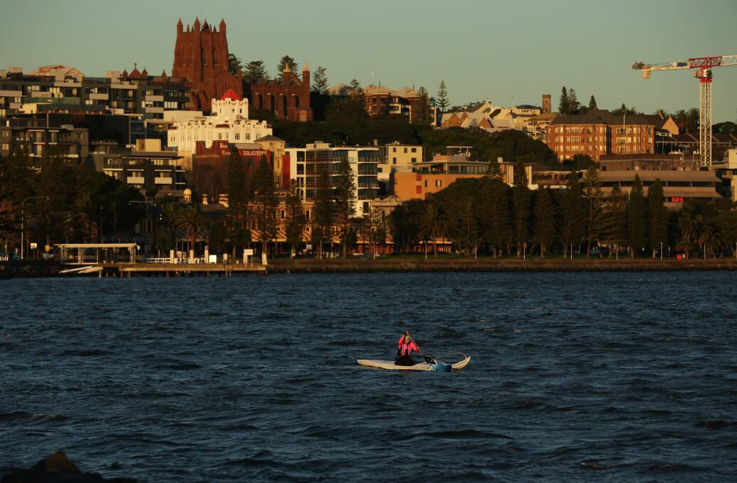 Outrigger canoe paddler Alaine Morris greets the day on Newcastle harbour. Picture: Simone De Peak