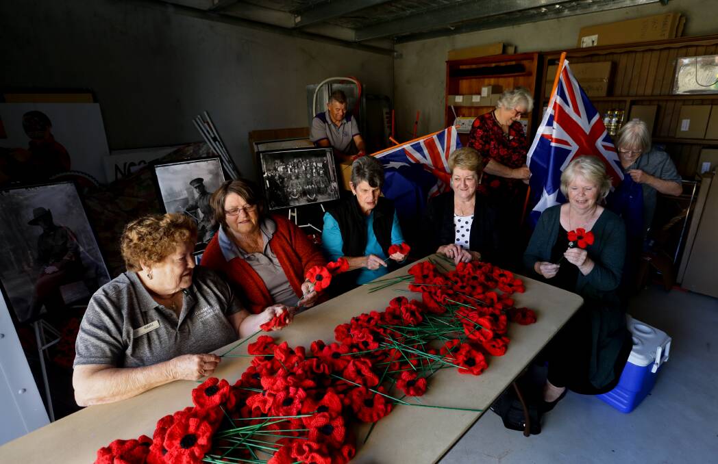 TEAM EFFORT: Kurri Kurri community members sort knitted and crocheted poppies, while others prepare the flags for Anzac Day.
