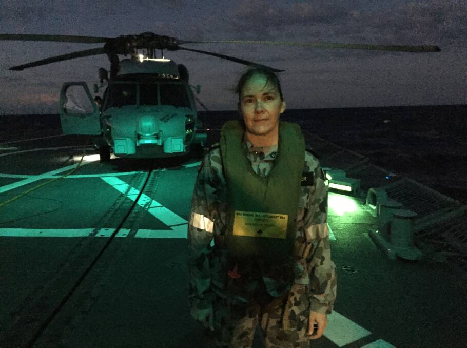 Petty Officer Sarah Waller on the flight deck of HMAS Newcastle, with the helicopter, nicknamed "Hunter", in the background. Picture: Scott Bevan
