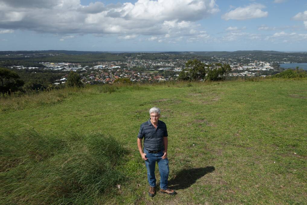 Munibung Hill Conservation Society member Fergus Hancock stands on the top of the hill, with a view of Warners Bay behind him. Picture: Max Mason-Hubers