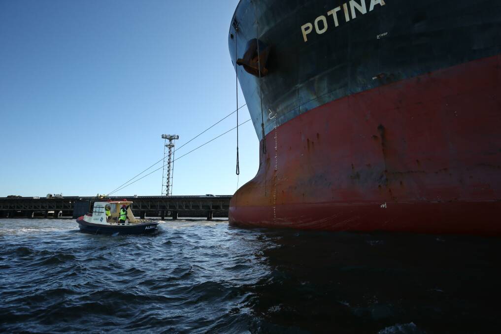 The crew of "Almax" wait to receive a line being lowered from the bulk carrier "Potina", as the coal ship is tied up at Kooragang. Pictures: Simone De Peak 