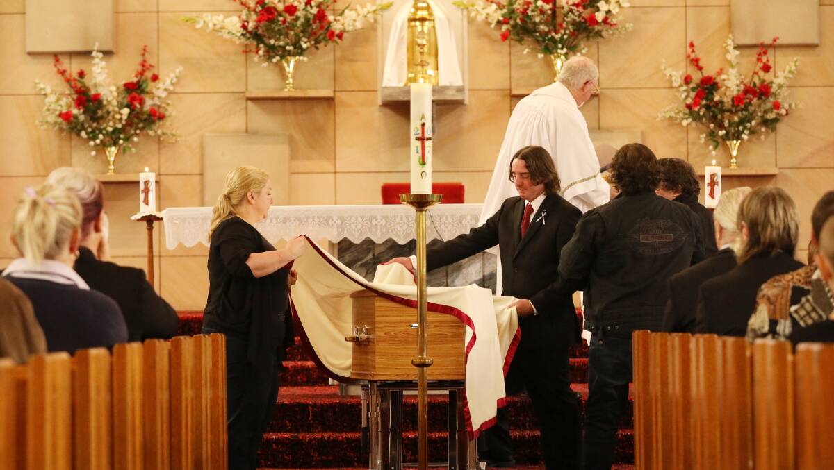 SOLEMN SERVICE: Jenny Allen and Michael Sessions place the pall on the casket of their brother, Bernie Sessions. Picture: Max Mason-Hubers