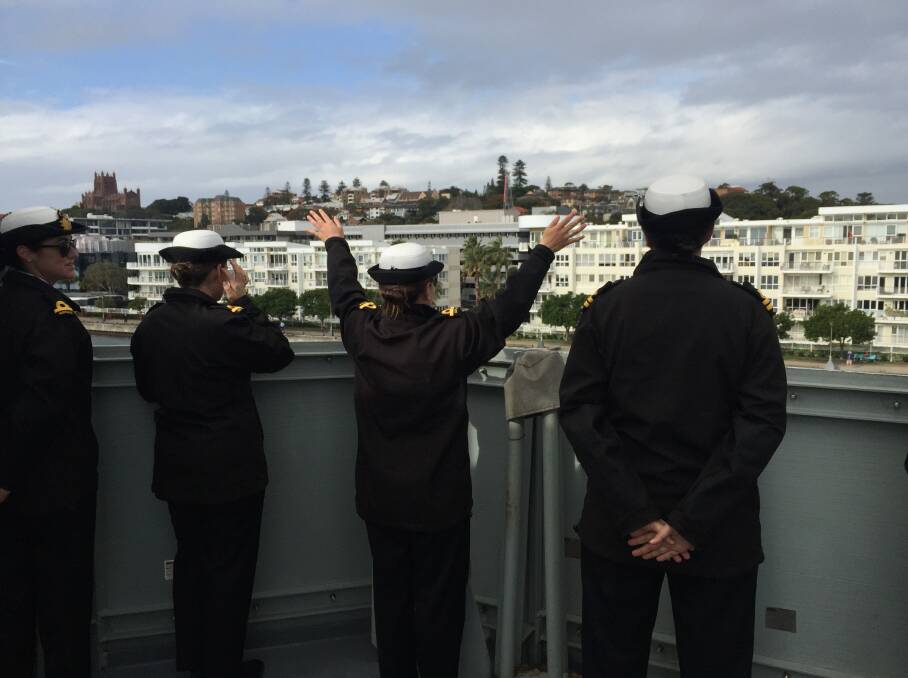 FAREWELL: Officers on HMAS Newcastle wave as the ship departs the city. 