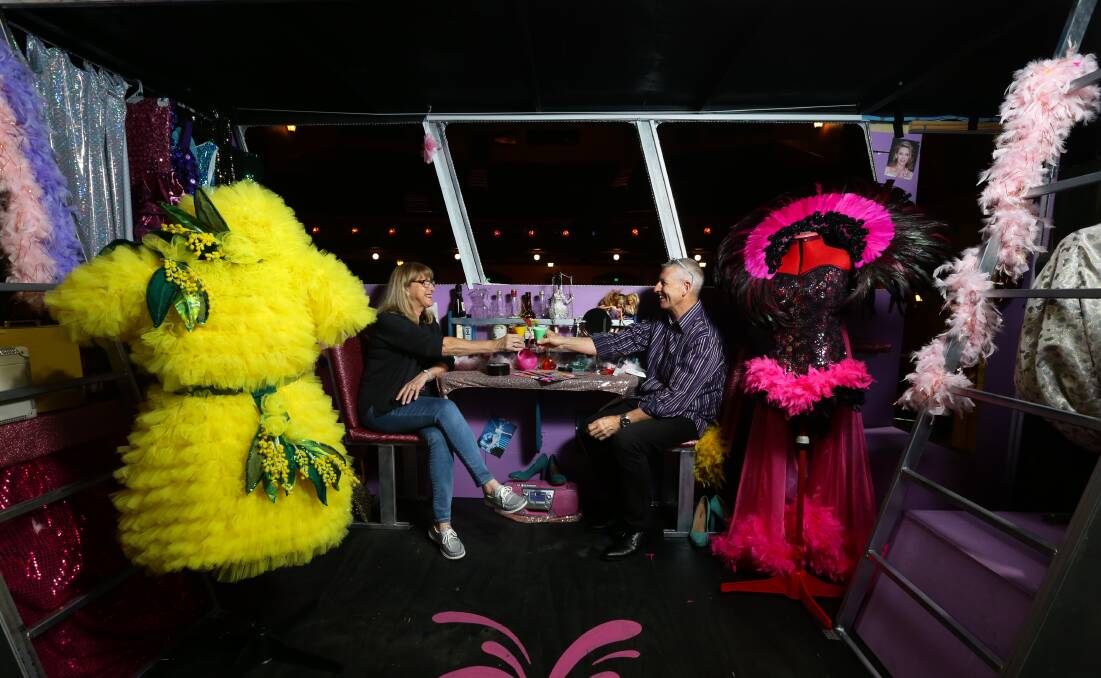 ALL ABOARD: Costume designers Bev Fewins and Steve Harrison, with two of their creations, sit on Priscilla the bus. Picture: Jonathan Carroll