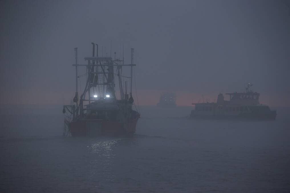 A fishing trawler and the Stockton ferry on the harbour on a foggy morning. Picture: Simone De Peak
