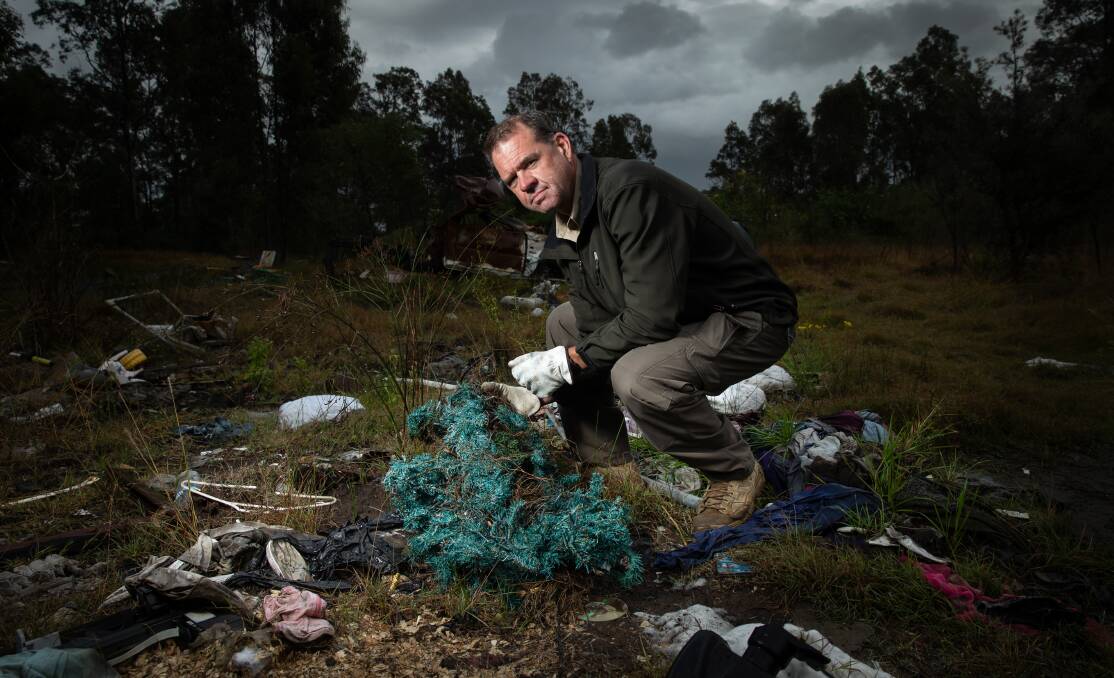 SEARCHING: RID investigator Peter White inspecting rubbish, including a Christmas tree, dumped at Tenambit. Picture: Marina Neil