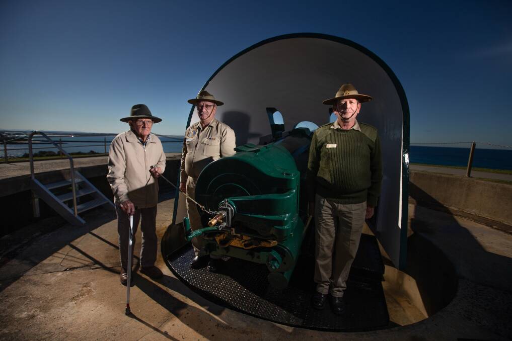 World War Two veteran David Needham fires the gun, with Fort Scratchley Historical Society volunteers Dale Hogan and Geoff Hollis looking on. Picture: Marina Neil