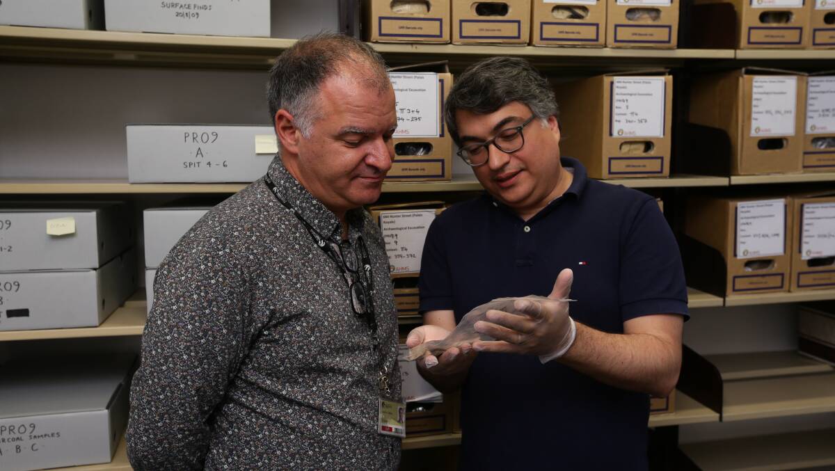 Archivist Gionni Di Gravio and conservator Dr Amir Moghadam inspect an artefact.Picture: Jonathan Carroll